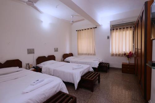 a room with three beds and chairs and windows at YWCA International Centre in Mumbai