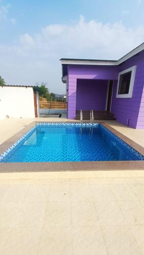 a large swimming pool in front of a purple building at Vihanka villa in Tāhārpur