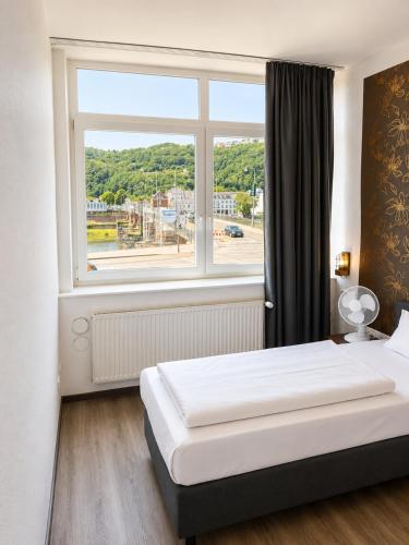 ein Schlafzimmer mit einem Bett und einem großen Fenster in der Unterkunft Hotel Constantin Trier in Trier