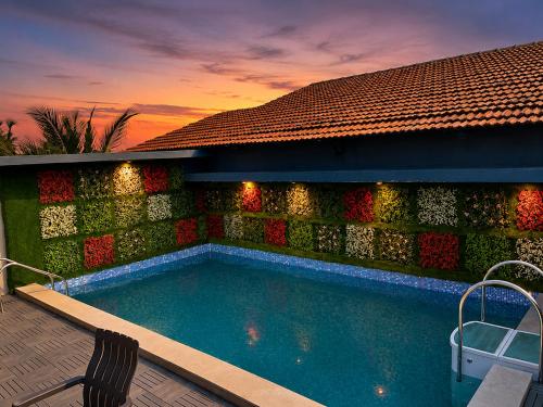 a swimming pool in front of a wall with a sunset at Hotel The Golden Sands, Located on Calangute Main Road in Calangute