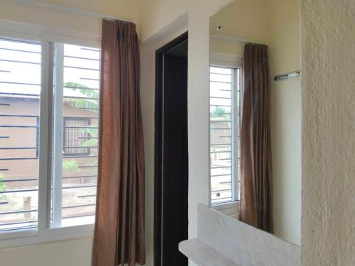 a mirror in a room with two windows and a balcony at Tutti Cafe in Hampi