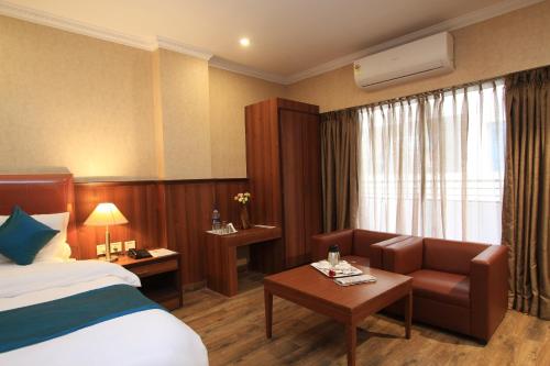 a hotel room with a bed and a couch at Hotel Noor Empire International Kormangala in Bengaluru