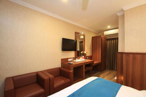 a hotel room with a bed and a desk and a television at Hotel Noor Empire International Kormangala in Bengaluru