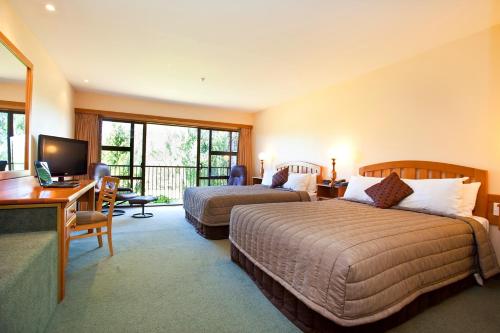 a hotel room with two beds and a desk at Distinction Mackenzie Country Hotel in Twizel