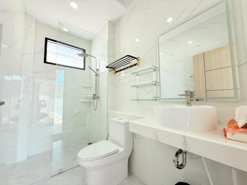 a white bathroom with a toilet and a sink at Nook Villa in Ban Khlong Mae Nam