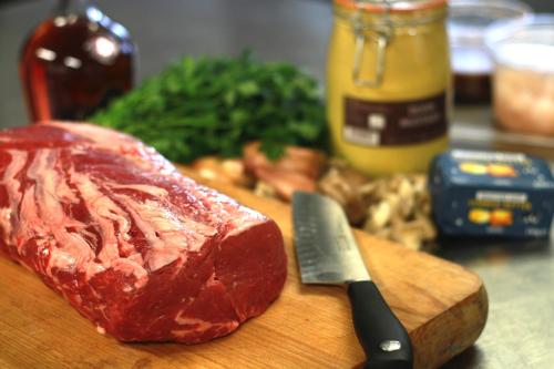 a piece of meat on a cutting board with a knife at Halfway House Inn in Wadebridge