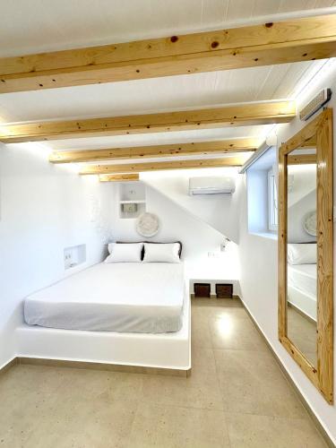 a white bedroom with a white bed and a mirror at Sul Mare Suite in Agia Kiriaki Beach
