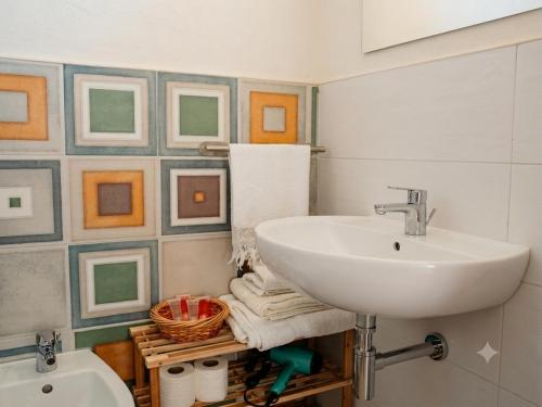 a bathroom with a sink and pictures on the wall at Andasì in Pachino