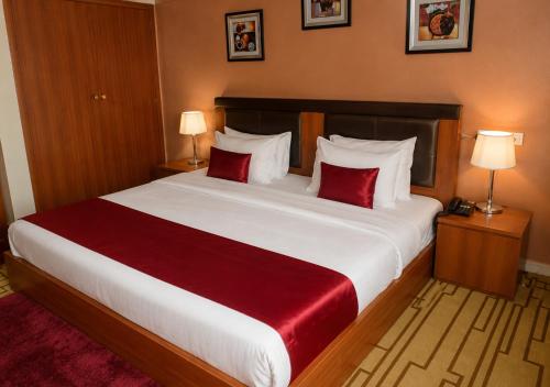 a bedroom with a large white bed with red pillows at Aneks Ibro Hotel, Wuse Zone 5, Abuja in Abuja