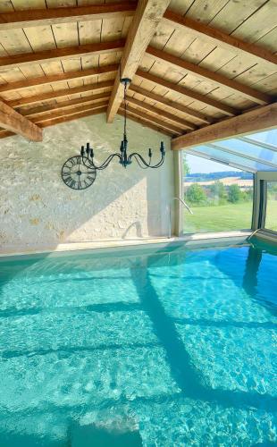an indoor swimming pool with a chandelier in a house at Domaine Léa Chanflaur - Spa - La maison du bonheur in Terraube