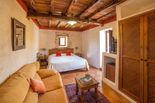 a living room with a bed and a couch at Hotel Rural Can Pujolet in Santa Agnès de Corona
