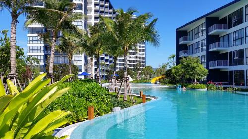 a resort swimming pool with palm trees and buildings at Baan Thew Talay Blue Sapphire in Cha Am