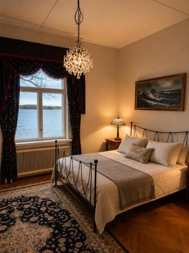 a bedroom with a bed and a window and a chandelier at Källgård in Lohja