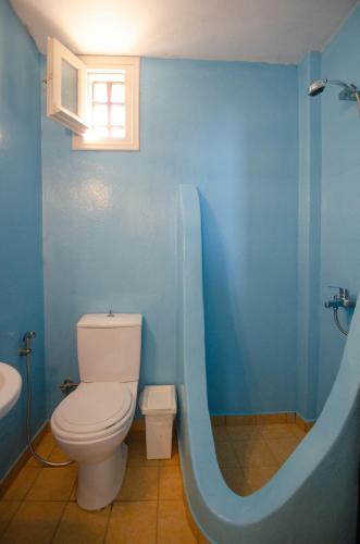 a blue bathroom with a toilet and a bath tub at Mylopota apartment IIΙ in Mylopotas