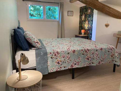 a bedroom with a bed with a floral bedspread at Gîte de Lafeuillade in Montech