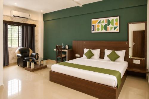 a bedroom with a bed and a desk and a chair at Hotel Vijaya Suites in Manipal