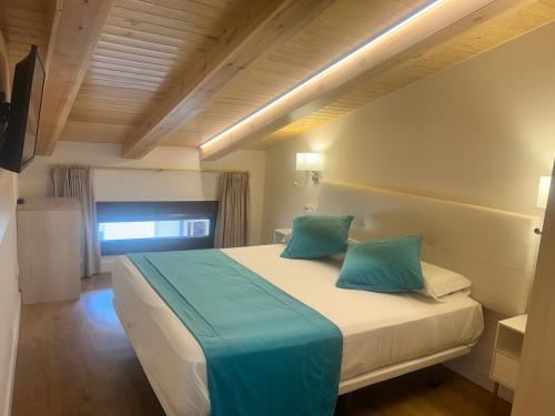 a bedroom with a large bed with blue pillows at Hotel SAIOLA in Camprodon