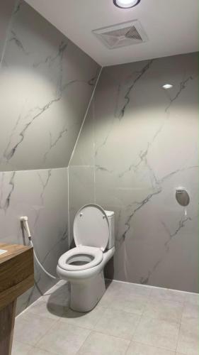 a bathroom with a white toilet and marble walls at سكون in Al Baha