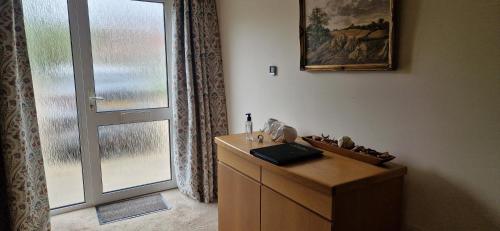 a room with a dresser and a door with a window at Blackberry Cottage, Wood Farm in Shipdham