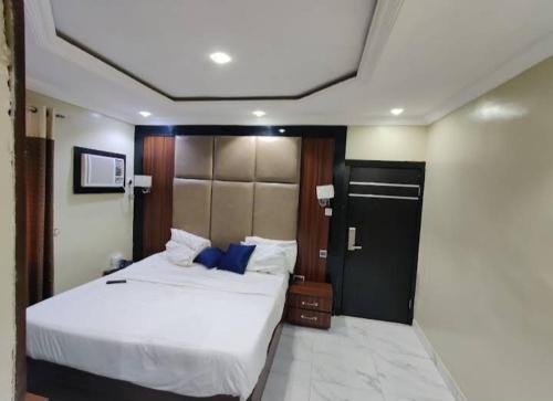 a bedroom with a large white bed with blue pillows at Six Diamond Hotel in Ikeja