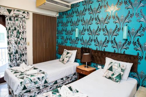 two beds in a room with blue wallpaper at Golden Sun Hotel - Hurghada in Hurghada