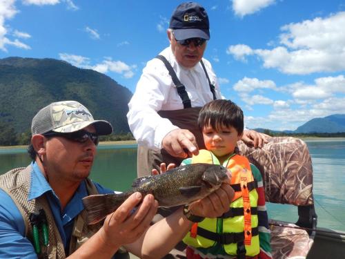 a group of people holding a fish on a lake at Barraco Lodge in Puelo