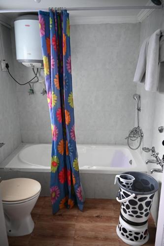a bathroom with a tub and a toilet and a shower curtain at Himalayan Cottages Pahalgam in Pahalgām