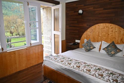 a bedroom with a bed and a window at Himalayan Cottages Pahalgam in Pahalgām