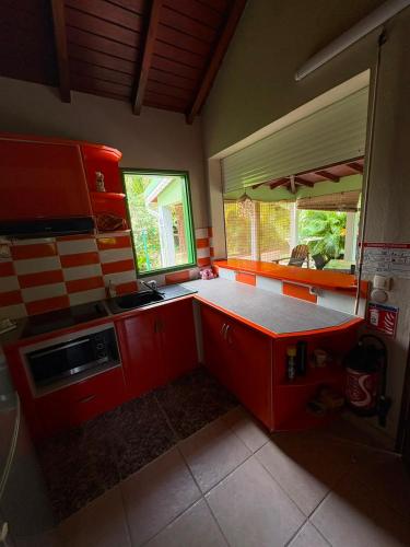 a kitchen with red cabinets and a counter top at Gite d'Arles Bungalow "Orchidée" in Le Moule