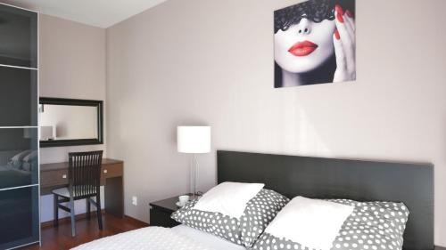 a bedroom with a bed and a desk with a picture of a woman at Apartament Słoneczny in Darłówko