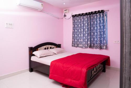 a bedroom with a bed with a red blanket on it at My3 Dwarkamai in Vijayawāda