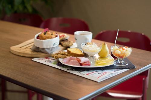 a wooden table with a plate of food on it at Campanile Villeneuve-Sur-Lot in Pujols Lot et Garonne
