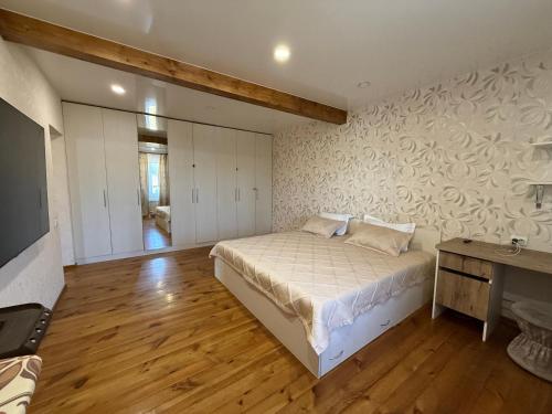 a bedroom with a bed and a desk and a television at Дом с бассейном и мангальной зоной in Ustʼ-Kamenogorsk