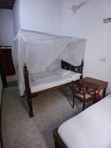 a room with a bed and a bench and a table at Lamu Sunsail Hotel in Lamu