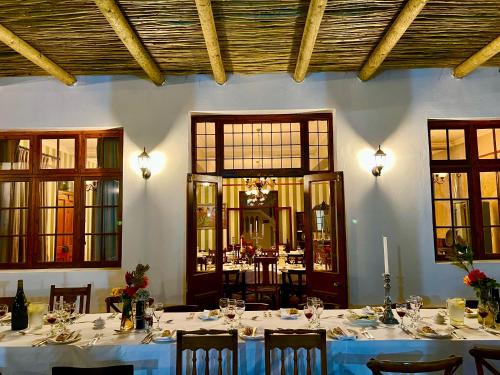 a dining room with white tables and chairs and windows at KAROO ART HOTEL 4 Star in Barrydale