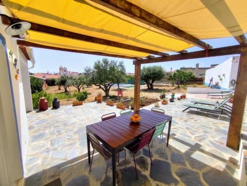 a patio with a table and chairs under a yellow umbrella at Refúgio do Artur - Casa no Campo in São Marcos do Campo