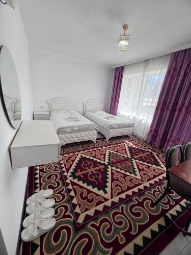 a living room with two beds and a rug at Ala-Too Hotel in Naryn