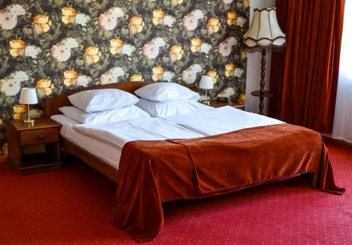 a bed in a bedroom with a floral wall at Hotel Metro in Kłodzko