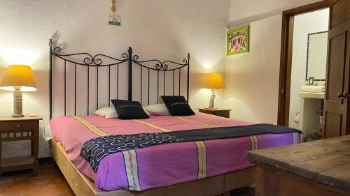 a bedroom with a large bed with a black and purple blanket at Hotel Casa Santos Guanajuato in Guanajuato