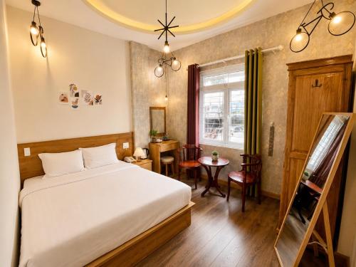 a bedroom with a bed and a table and a window at Mia House DaLat Hotel - Bống Stay in Da Lat
