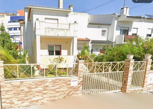 a white house with a fence in front of it at Rua Gama Barros 22 SUITE in Charneca