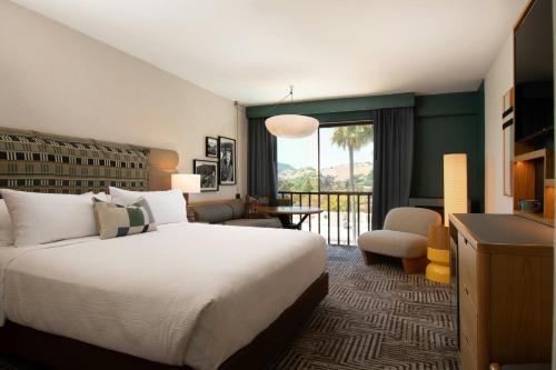a hotel room with a large bed and a balcony at Marin Hilltop Hotel in San Rafael
