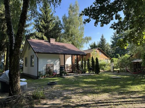 a small white house with a yard with trees at Domek Pod Świerkami in Wólka