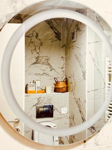 a circular mirror in a bathroom with marble walls at City nest Skopje in Skopje
