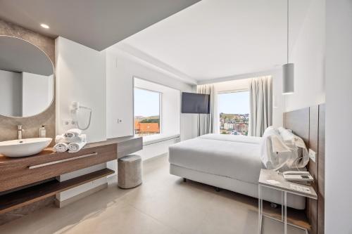 a bedroom with a bed and a sink and a mirror at Gran Hotel Suances Suites in Suances