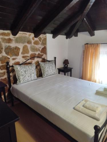 a large bed in a room with a stone wall at Lithos Villas Komitsa in Metókhion Koumítsas
