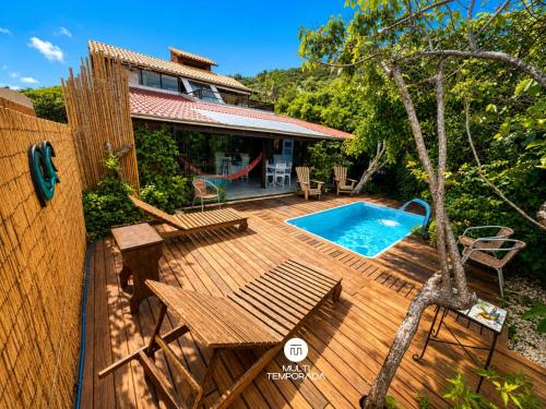 a wooden deck with a swimming pool and a house at Pousada Ondas da Grande - Penha/SC in Penha