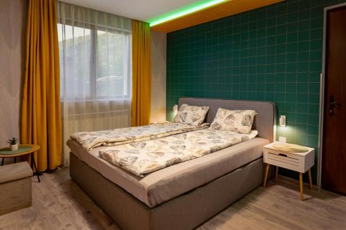 a bedroom with a bed with a green wall at Къща за гости Мурите in Sapareva Banya