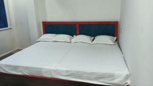 a large bed with white sheets and pillows at Hotel Janki Inn in Deoghar