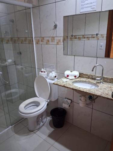 a bathroom with a toilet and a shower and a sink at Lebanon Praia Hotel in Tramandaí